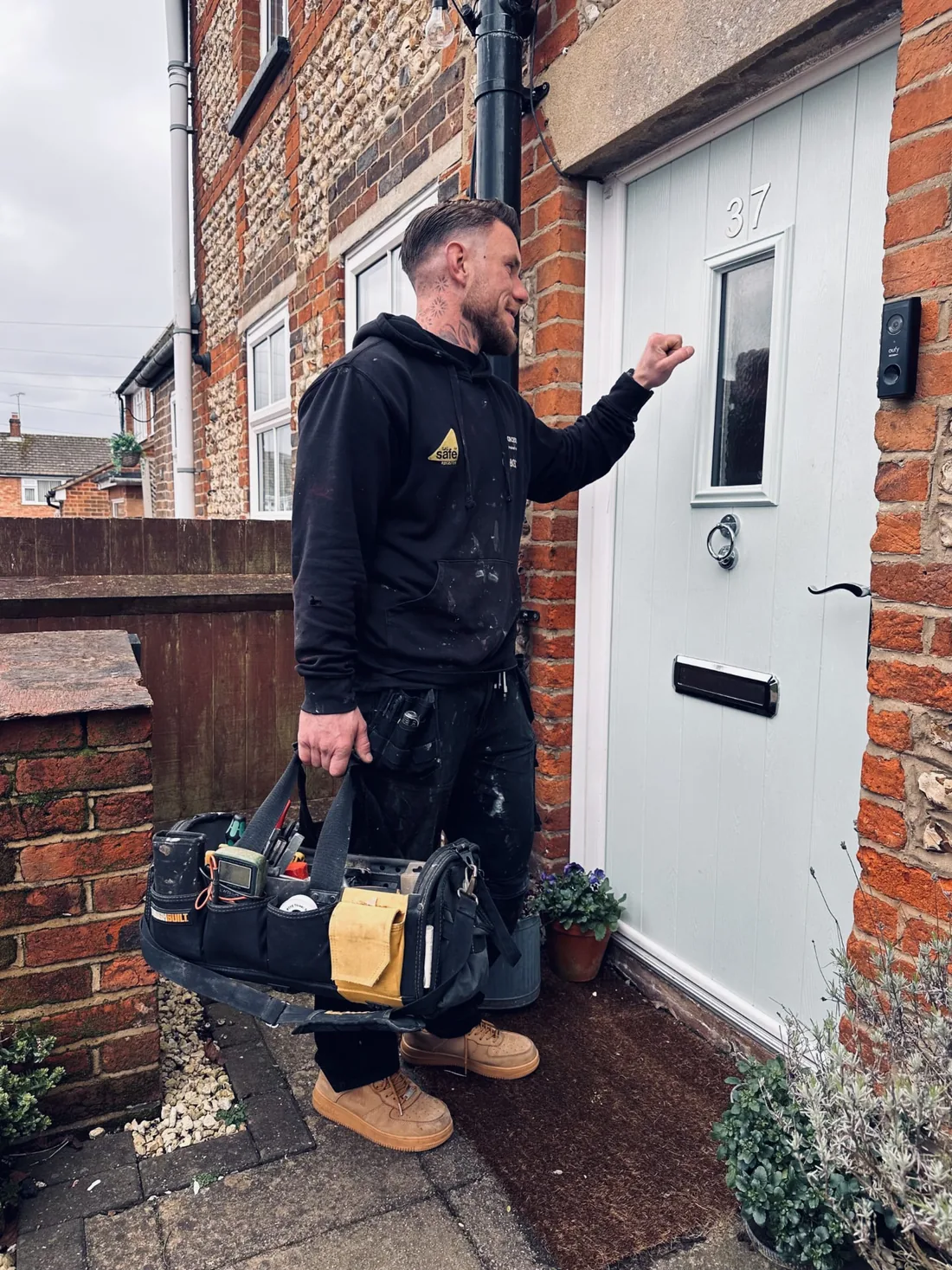 Plumbing and heating engineer arriving at a front door carrying tools