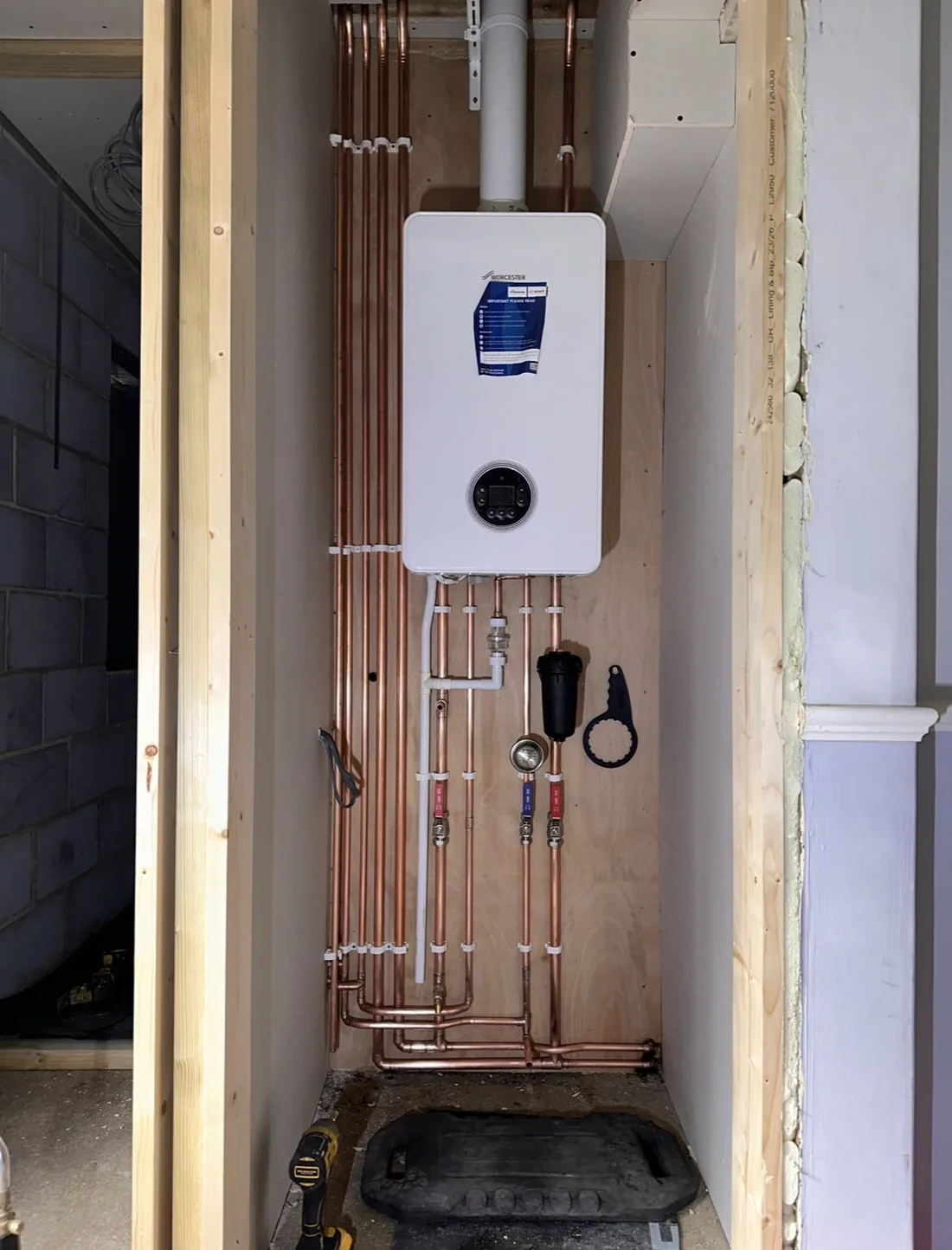 Wall-hung gas boiler installed with copper pipework and a filter fitted below