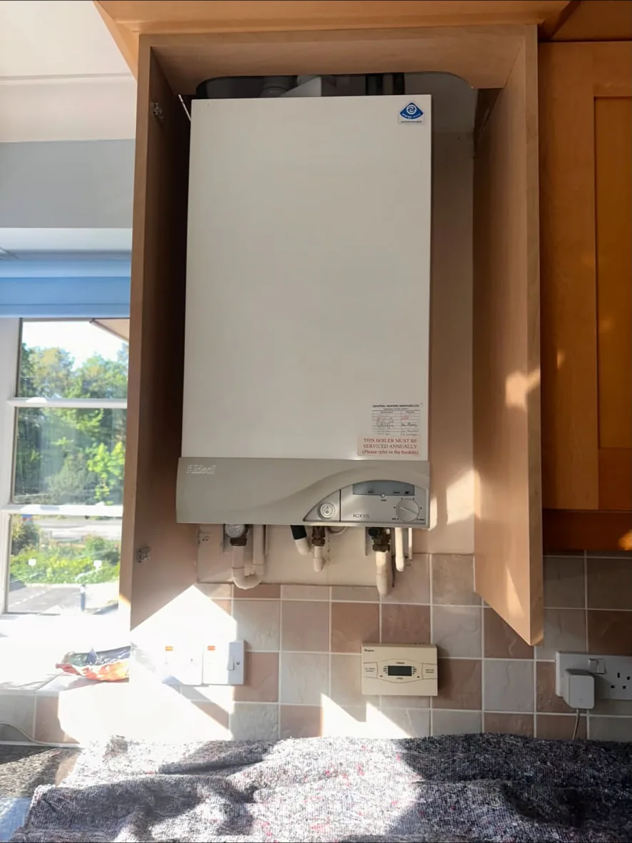 Older wall-hung gas boiler inside a kitchen cupboard before replacement