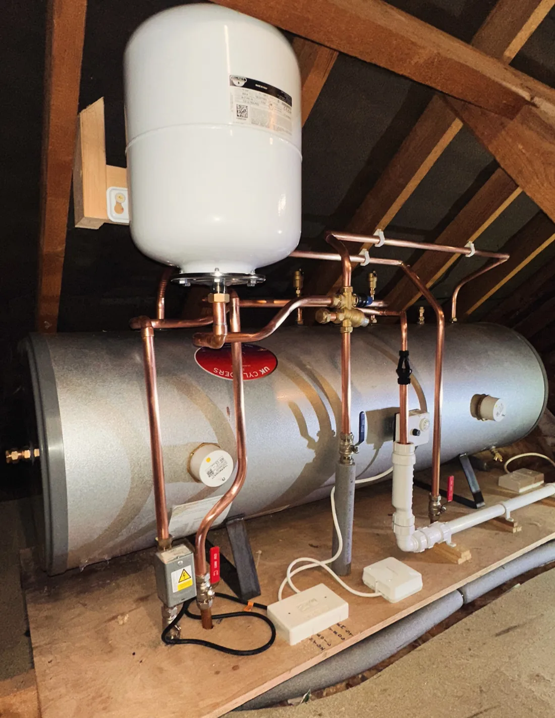 Horizontal hot water cylinder in a loft with an expansion vessel and copper pipework